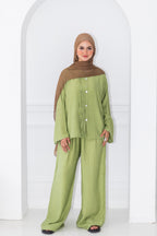 Woman wearing a green outfit with a brown hijab against a white background