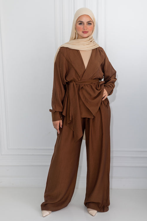 Woman wearing a brown outfit with a hijab against a white background