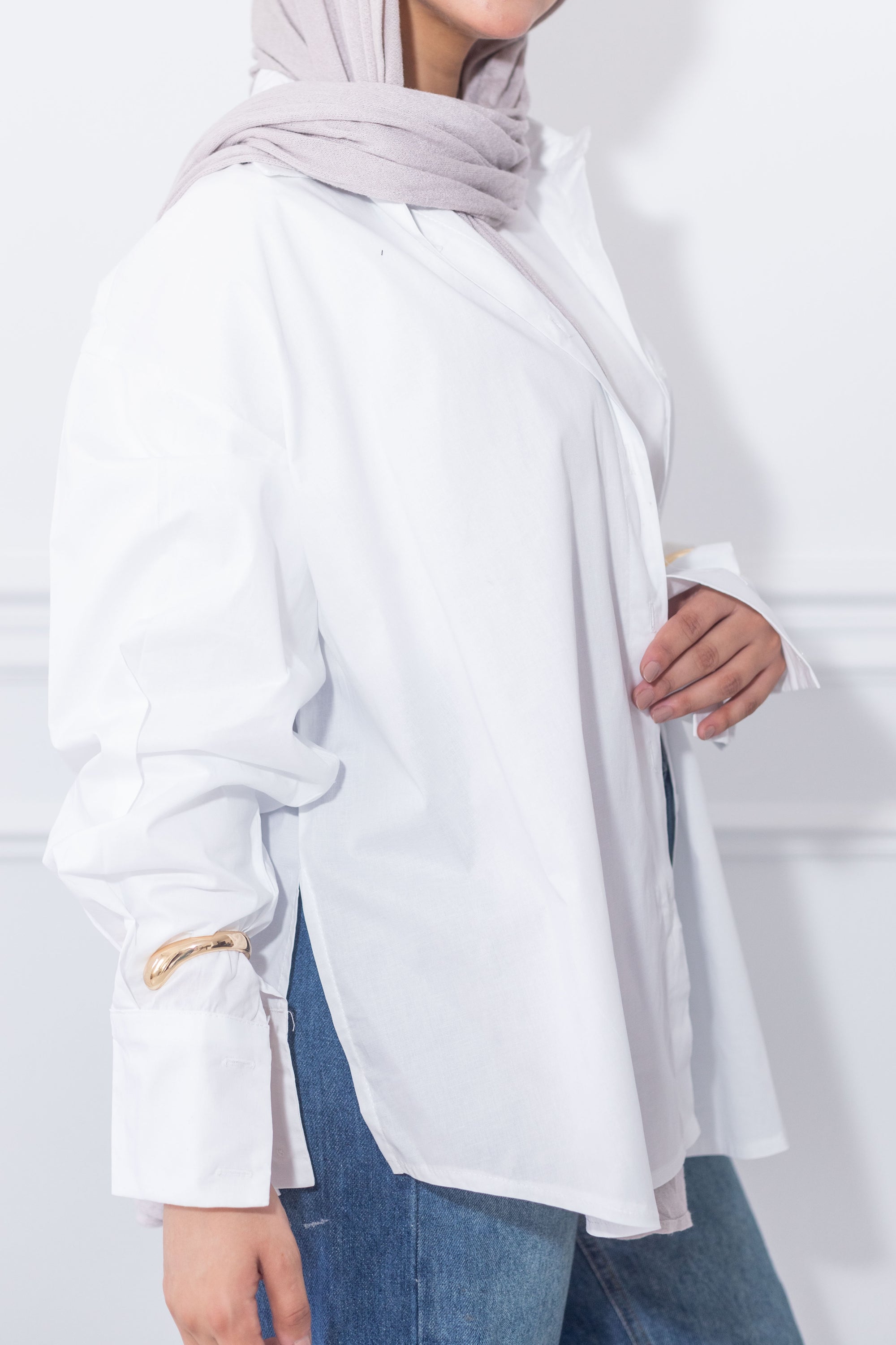 Person wearing a white outfit with a light gray hijab on a plain background