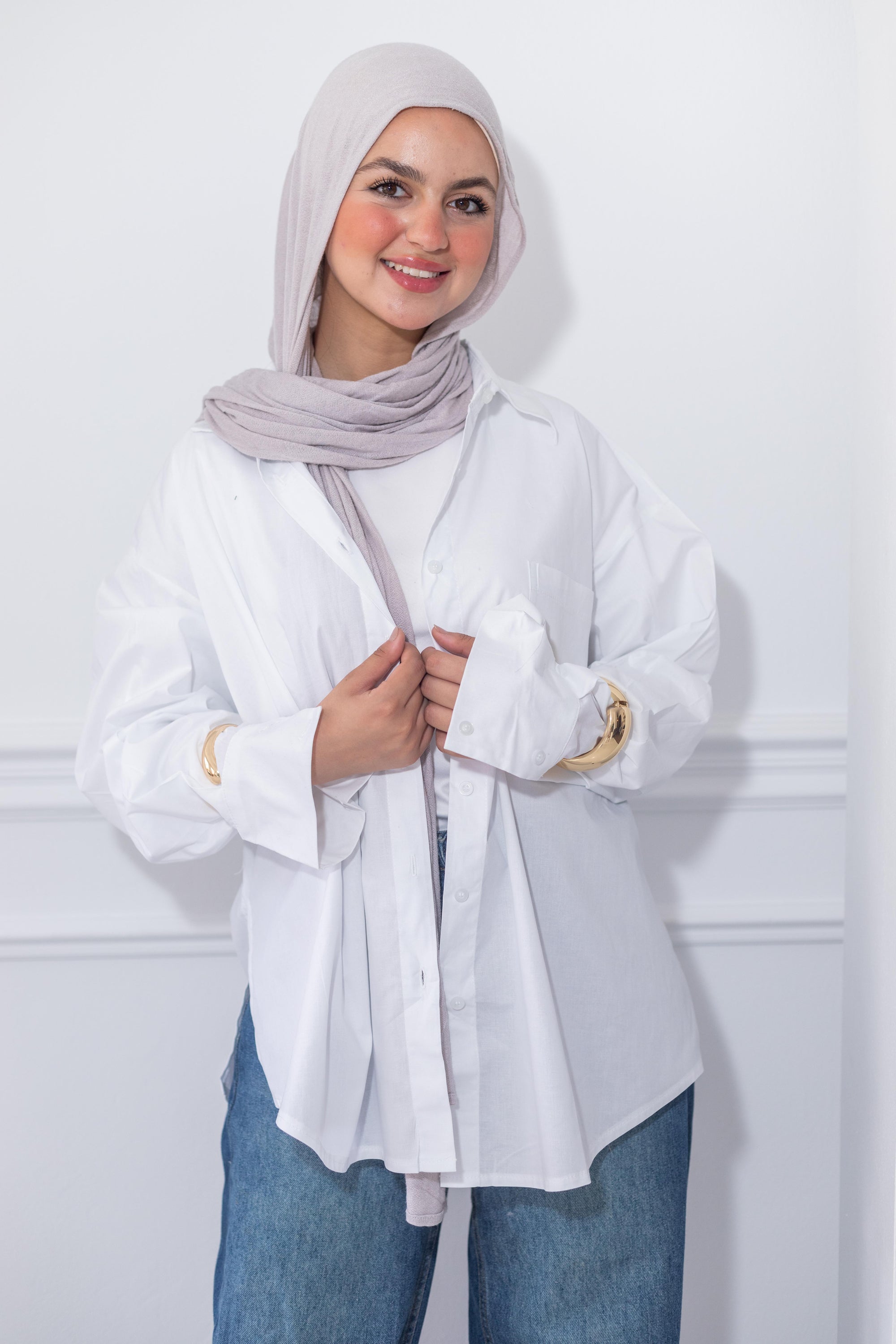 Woman wearing a white shirt and hijab against a white background