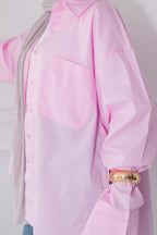 Pink blouse with a gold cuff detail on a plain background