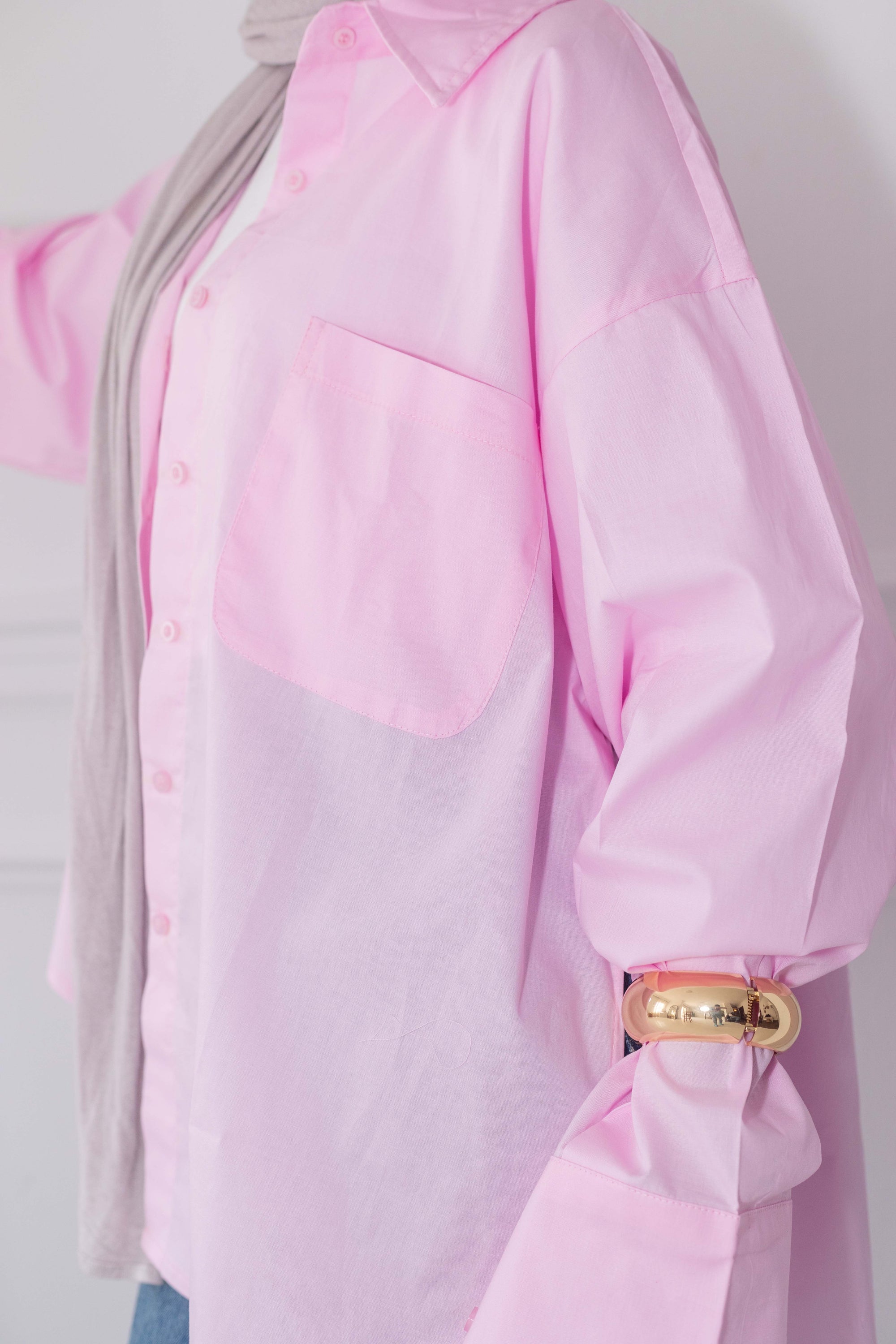 Pink blouse with a gold cuff detail on a plain background