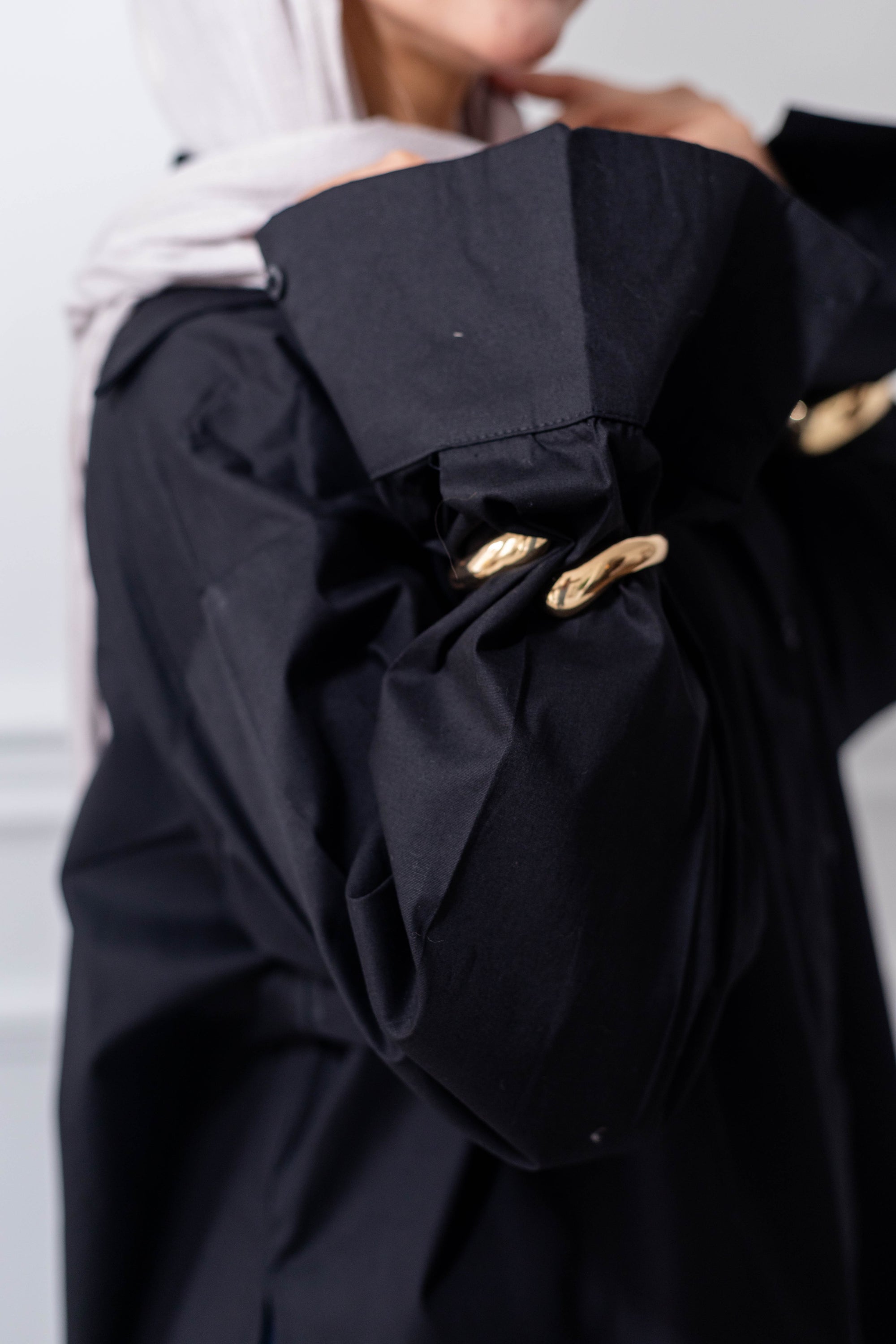 Black coat with gold buttons worn by a person, blurred background
