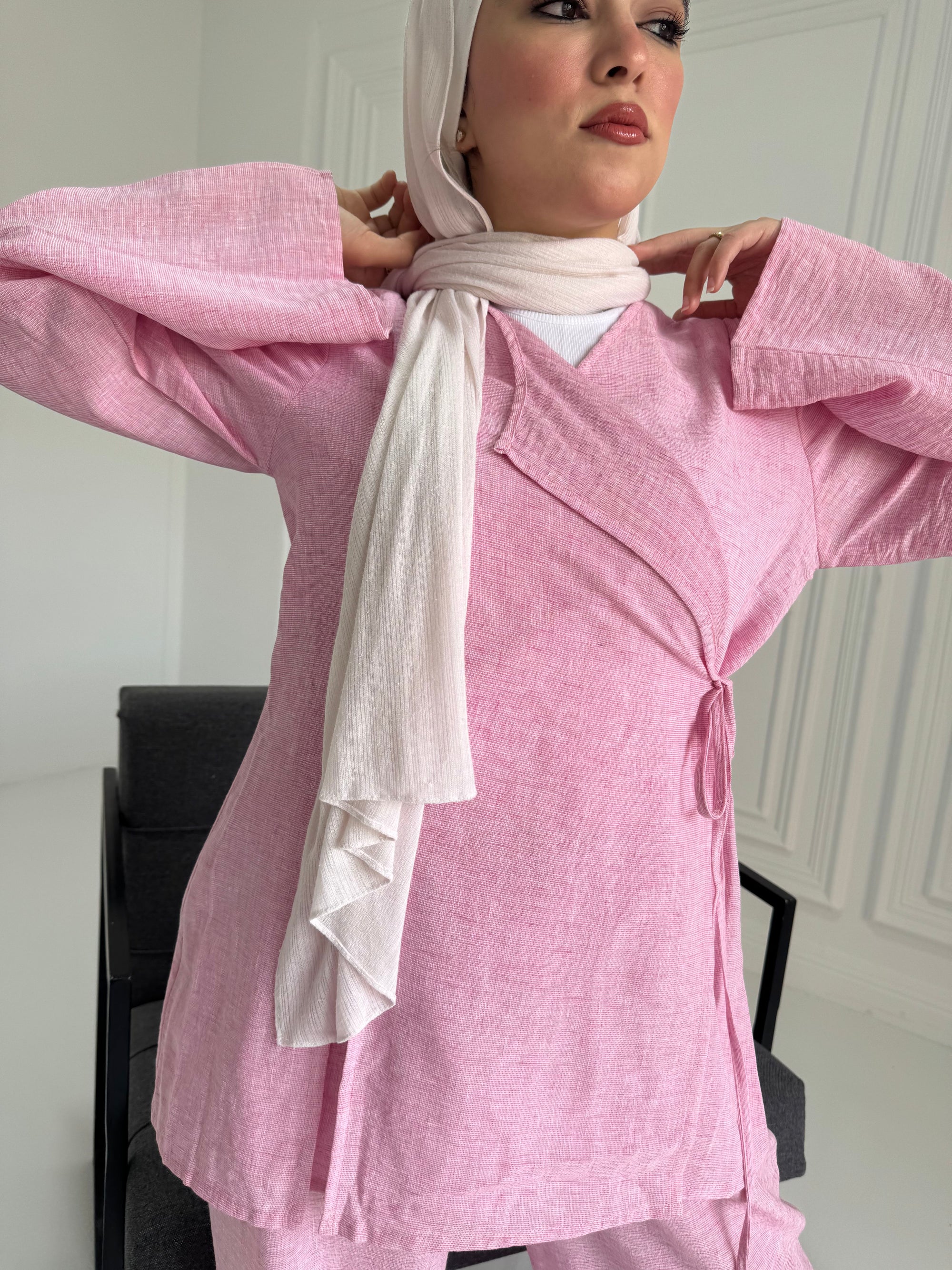 Person wearing a pink outfit with a white scarf in an indoor setting