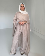 Woman wearing a beige outfit with a white hijab in a minimalistic setting