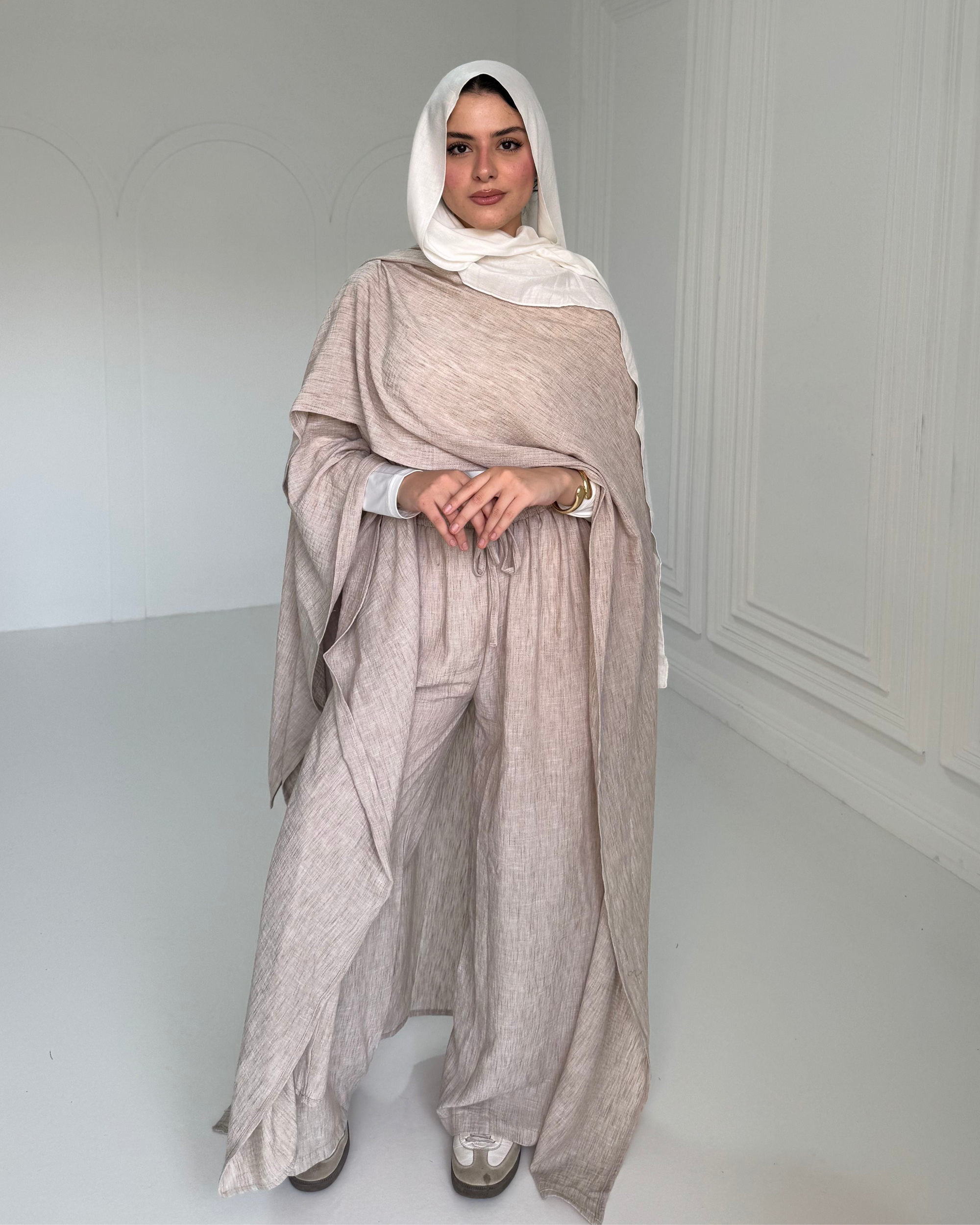 Woman wearing a beige outfit with a white hijab in a minimalistic setting