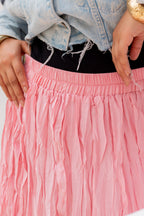 Close-up of a pink skirt with a person wearing a denim jacket and black top.