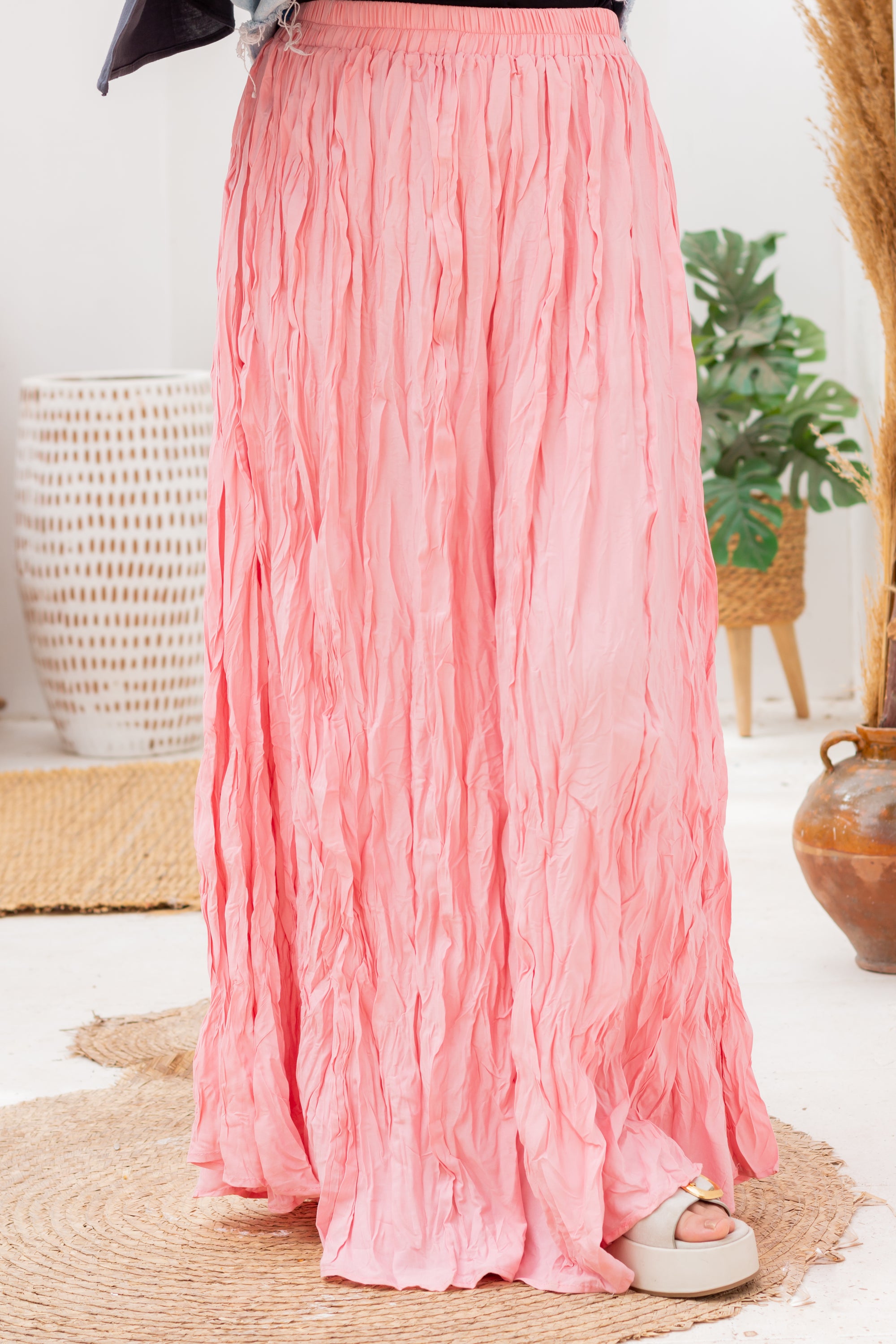 Person wearing a pink skirt in a home setting with plants and decor.