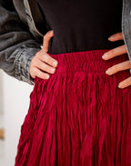Red fringed skirt with a person wearing it, focusing on the bottom half of the body.