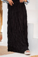 Black pleated skirt worn by a person indoors.