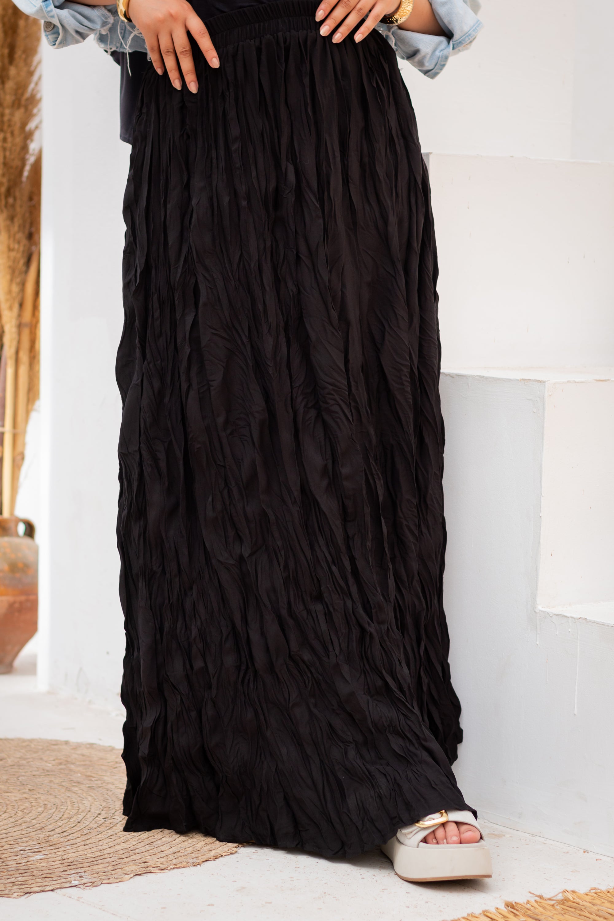 Black pleated skirt worn by a person indoors.