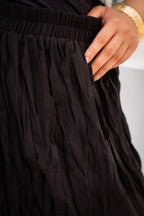 Close-up of a person wearing a black dress with a hand adjusting the waistband.