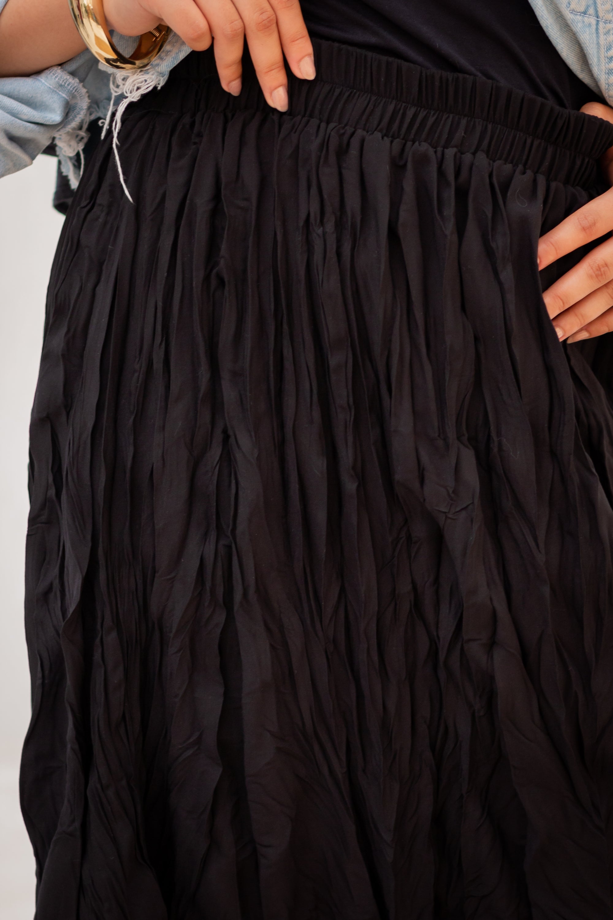 Black skirt with textured fabric held by a person against a white background