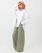 Person wearing a white shirt and green pants on a white background