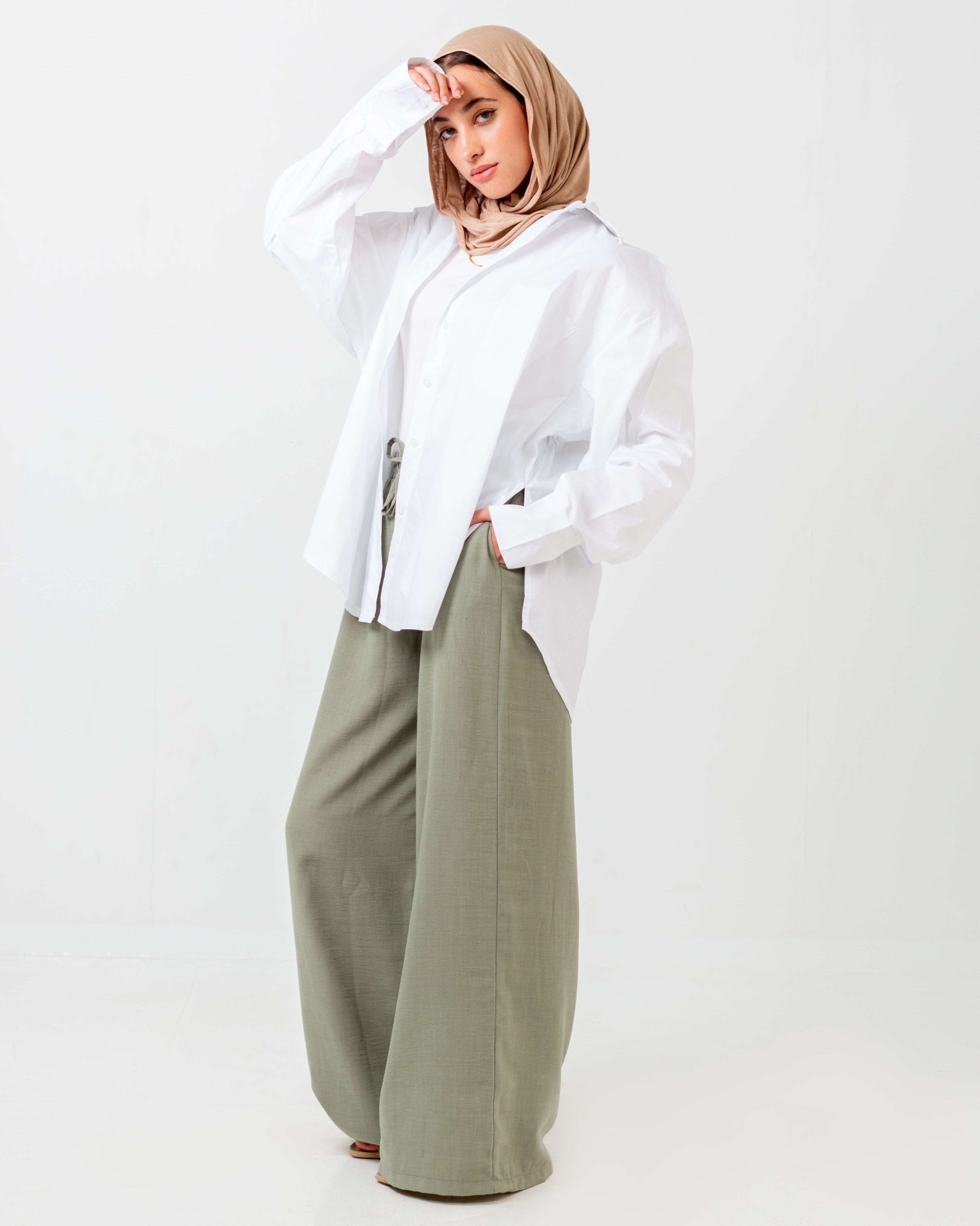 Person wearing a white shirt and green pants on a white background