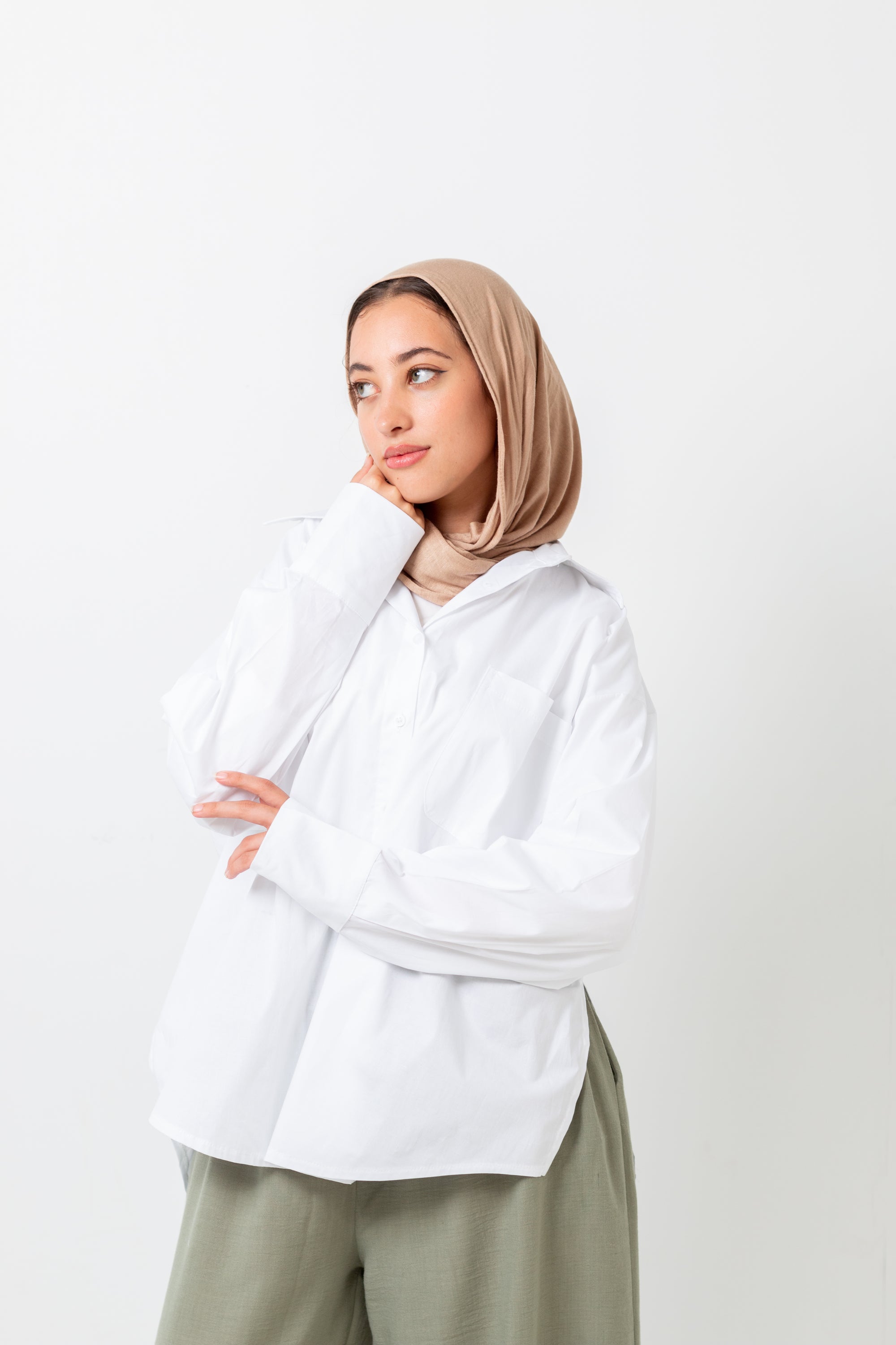 Woman wearing a beige hijab and white shirt on a white background