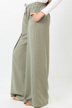 Person wearing olive green wide-leg pants on a white background