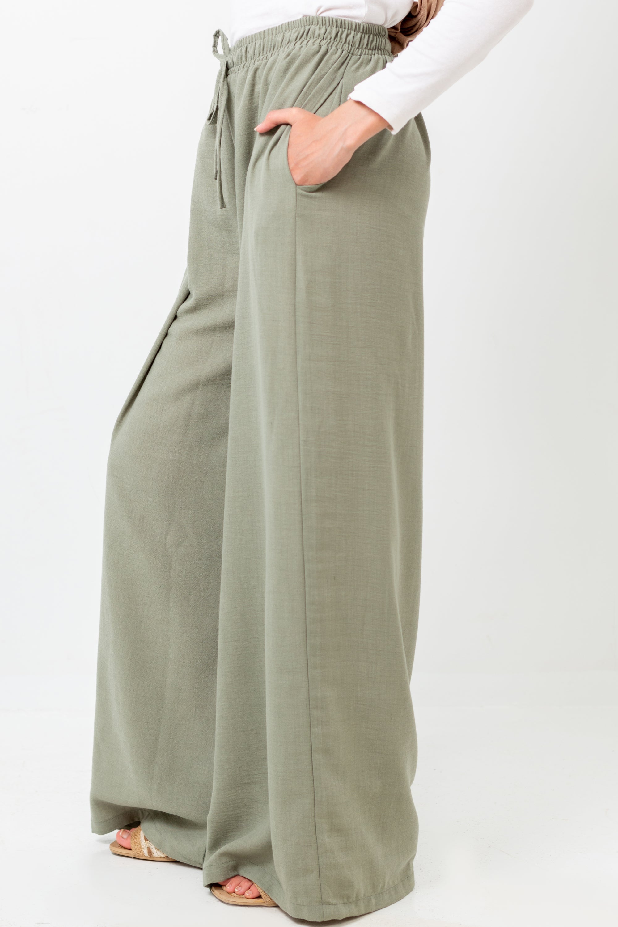 Person wearing olive green wide-leg pants on a white background