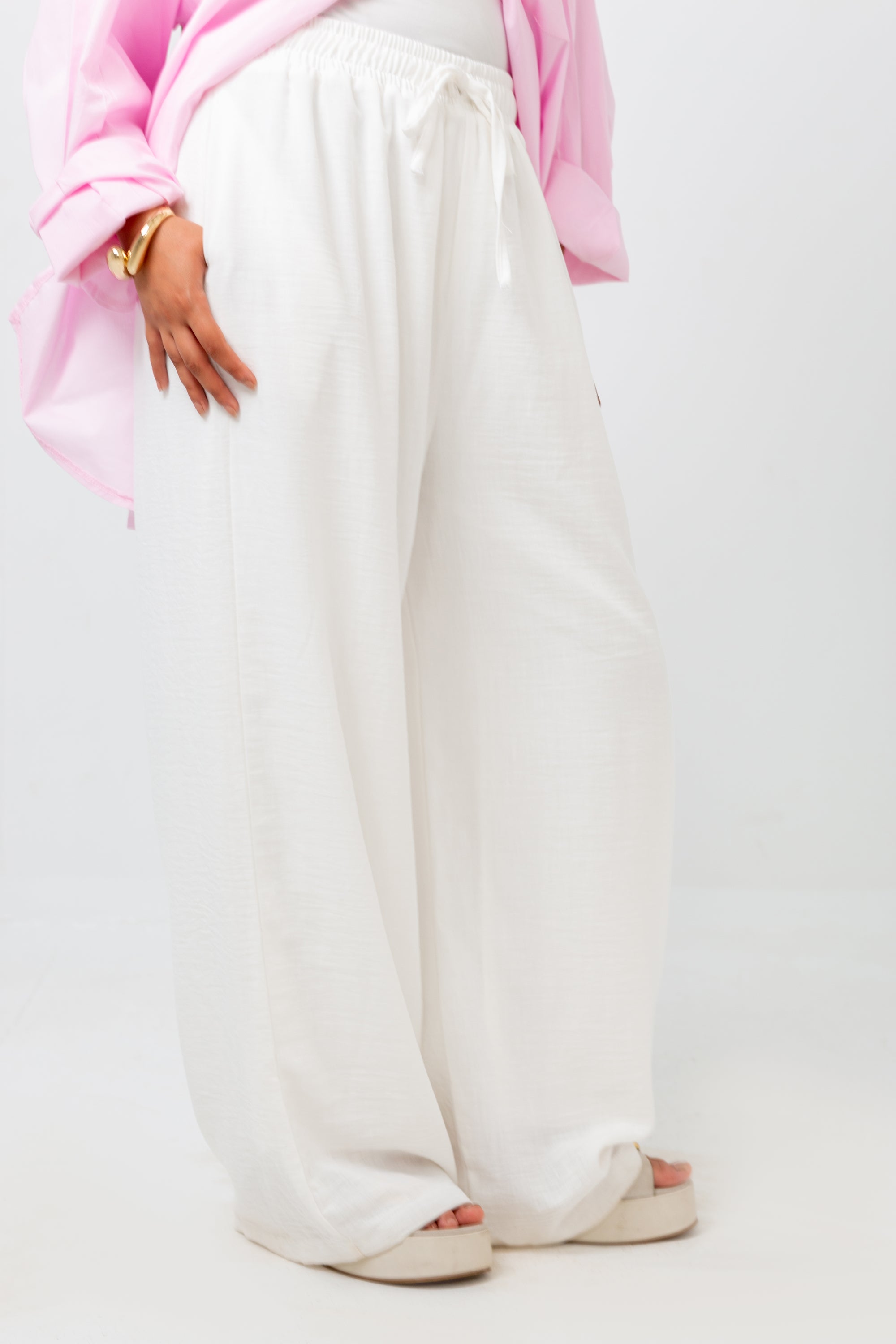 White wide-leg pants worn with a pink top on a white background
