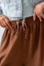 Brown pants with a light blue denim jacket worn by a person.