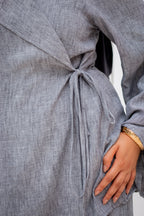 Gray dress with a tie waist worn by a person, with a blurred background